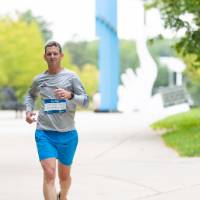 Participant running through campus by arch